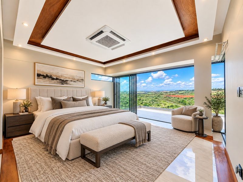 Luxurious master bedroom featuring a recessed ceiling with wood accents, ducted air conditioning, and expansive sliding glass doors opening to a scenic landscape view.