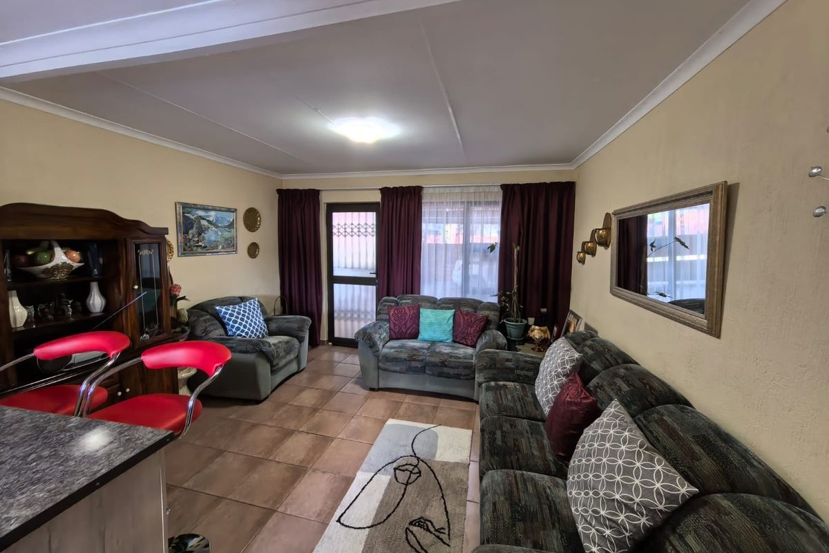 A comfortable living room featuring tiled flooring, coved ceilings, and direct access to the exterior through a secure glass panel door.