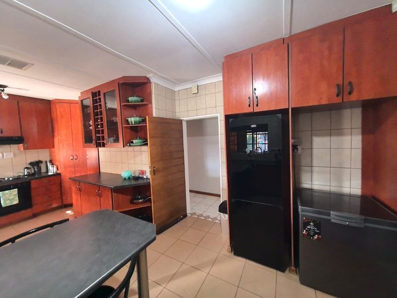 A functional kitchen featuring wooden cabinetry, tiled backsplash, and tiled flooring, offering a classic layout with integrated cooking appliances.