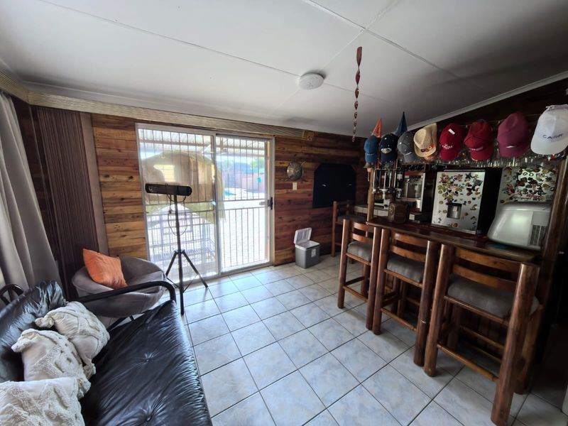 A dedicated bar area featuring a built-in wooden counter, tiled flooring, and sliding glass doors providing access to the outdoor pool area.