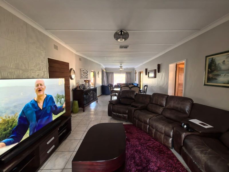 Spacious open-plan living and dining area featuring tiled flooring, a textured feature wall, and a ceiling fan, offering a versatile layout for family living.