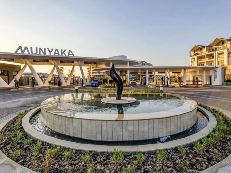 The main entrance to the Munyaka estate featuring a modern security gatehouse, paved driveway, and a central decorative water fountain.