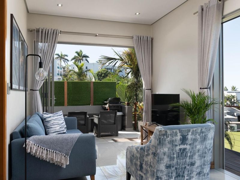 Bright open-plan living area featuring large sliding glass doors that open onto a private balcony, creating a seamless indoor-outdoor flow.