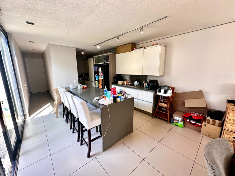 Open plan kitchen and living area featuring a large central island with stone countertops, modern cabinetry, and large sliding doors leading to the exterior.