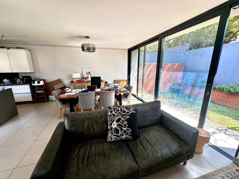 Spacious open-plan living and dining area featuring large sliding glass doors that provide seamless access to the rear garden and patio.