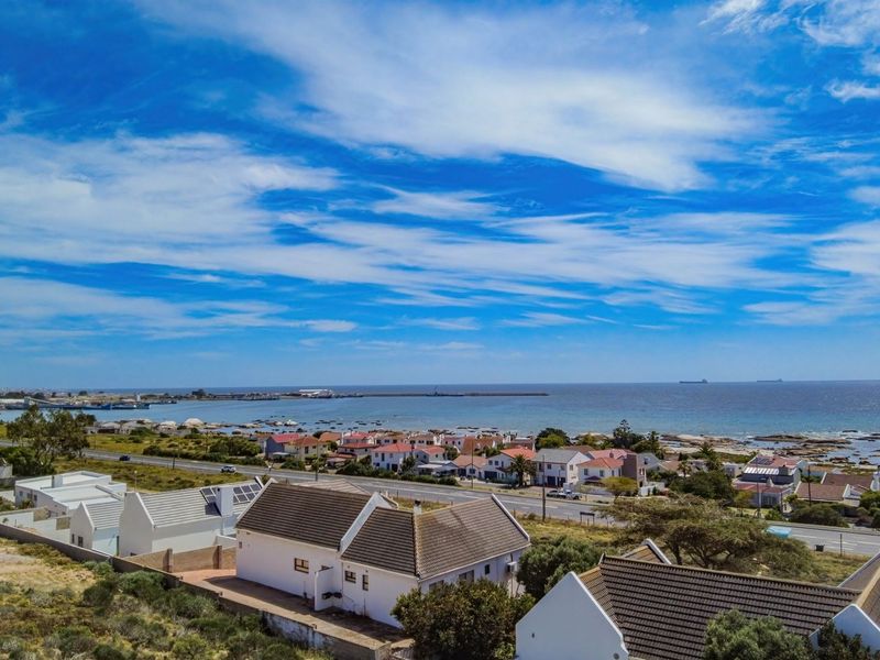 An elevated aerial view showcasing the coastal residential neighborhood, surrounding landscape, and proximity to the ocean.