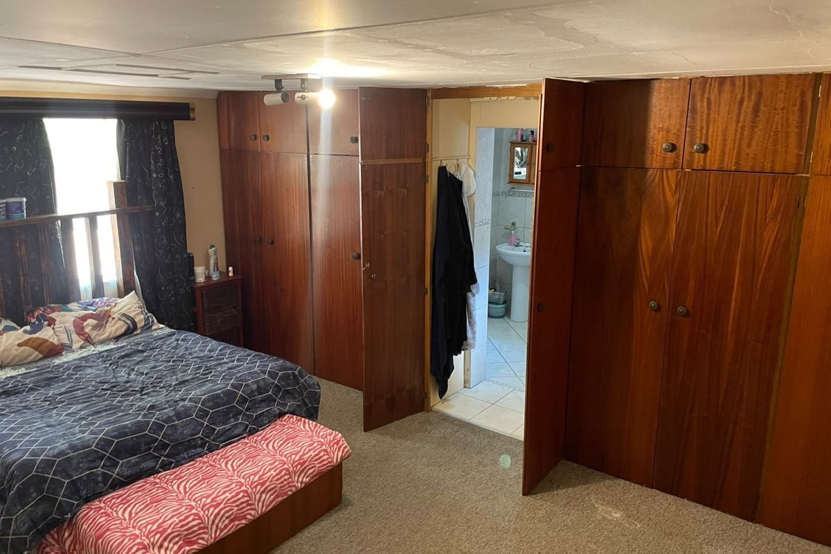 Bedroom featuring extensive built-in wooden cabinetry and direct access to an en-suite bathroom, requiring cosmetic updates to the ceiling and flooring.