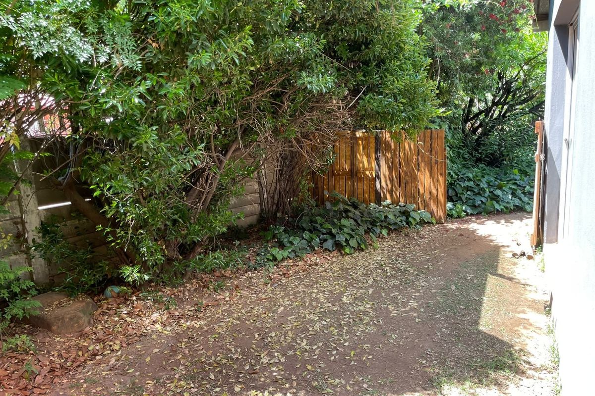 A rear garden area featuring a wooden fence and concrete boundary wall, currently requiring landscaping and maintenance.