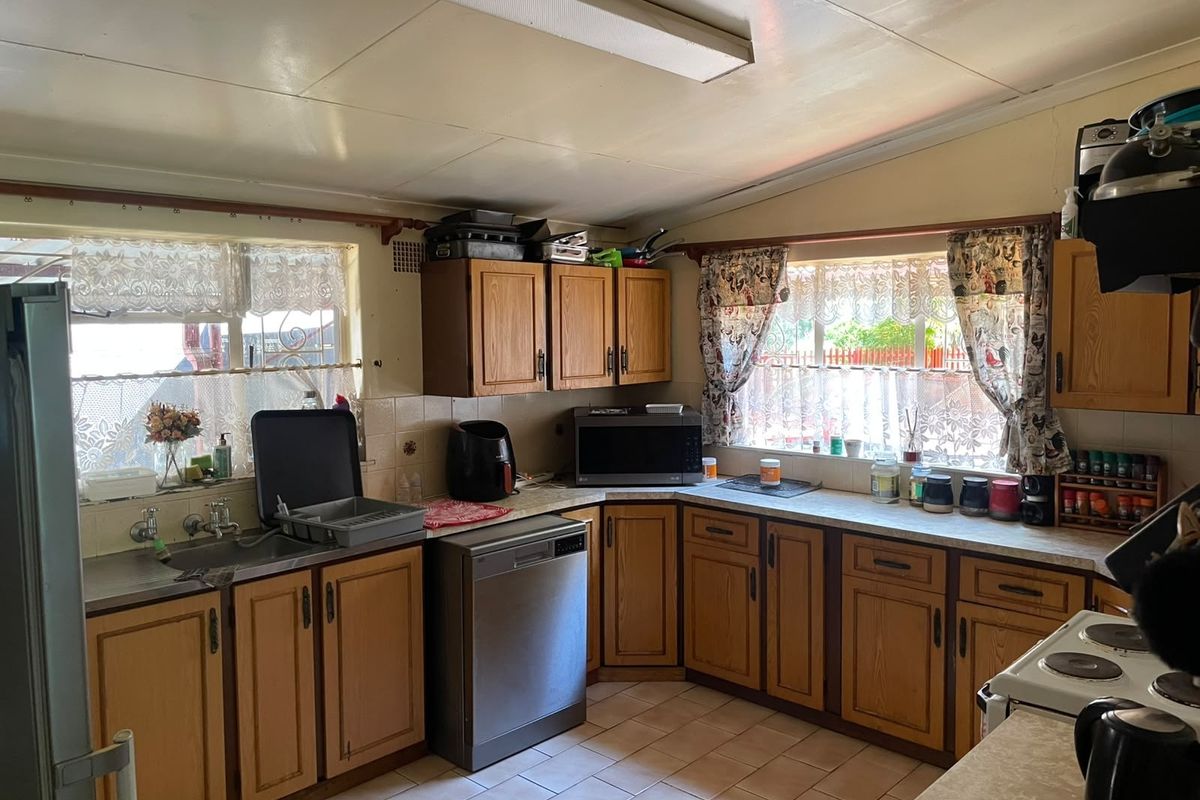 A functional kitchen featuring timber cabinetry, laminate countertops, and tiled flooring. The space offers a traditional layout with ample storage and natural light.