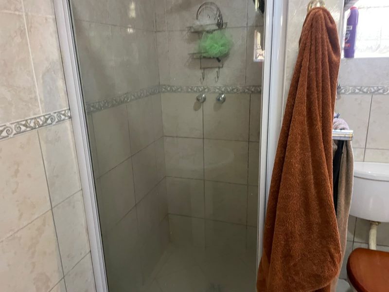 A functional bathroom featuring a tiled shower enclosure with a glass door and a standard toilet.