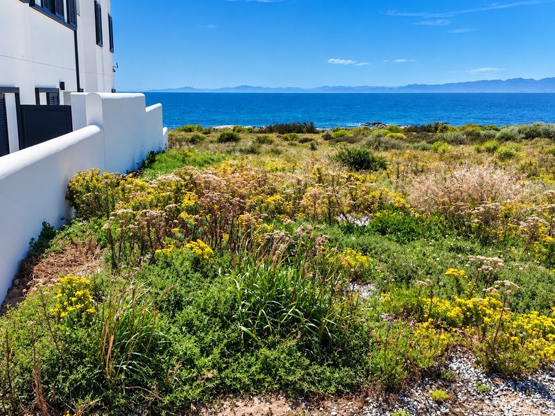 A scenic view of the ocean and coastal landscape, captured from the side of a residential property.