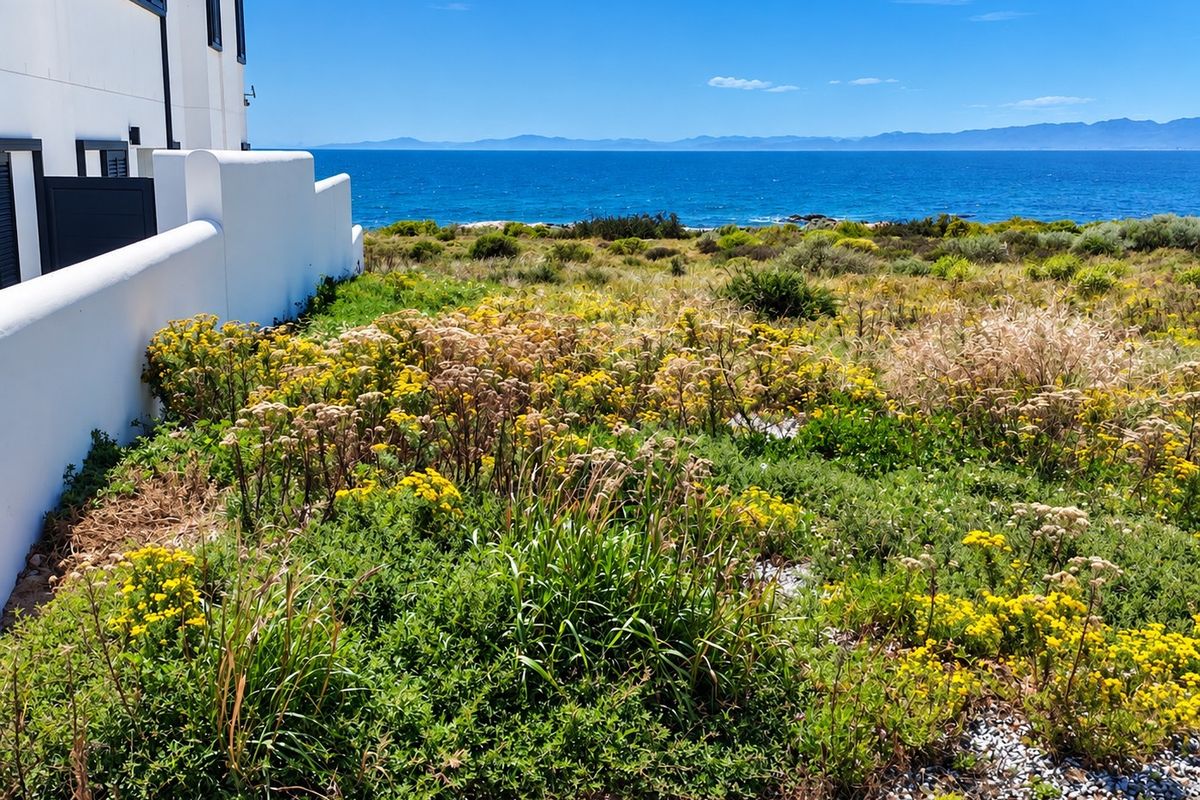 A scenic view of the ocean and coastal landscape, captured from the side of a residential property.