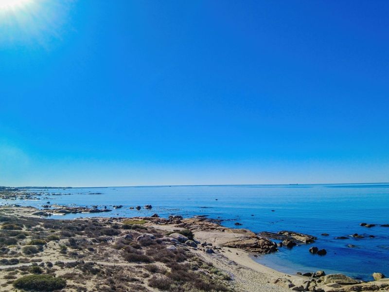 A scenic coastal view overlooking the ocean, rocky shoreline, and natural vegetation, highlighting the property's prime seaside location.
