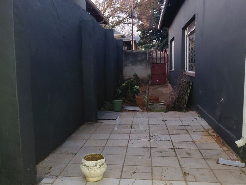 A narrow rear courtyard area featuring tiled flooring and high boundary walls, providing a private outdoor space with potential for landscaping or patio upgrades.