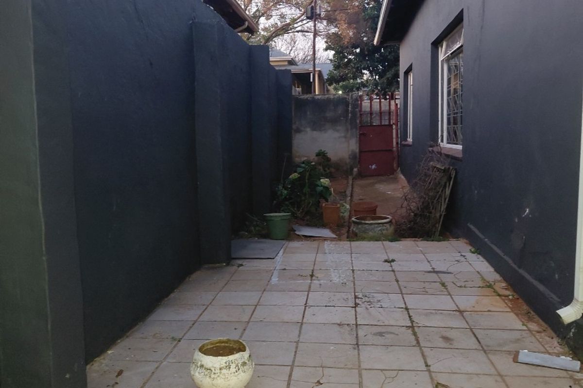 A narrow rear courtyard area featuring tiled flooring and high boundary walls, providing a private outdoor space with potential for landscaping or patio upgrades.