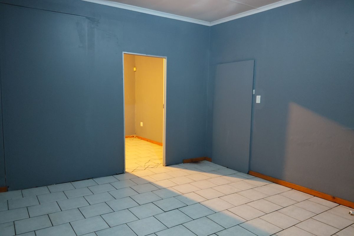An empty bedroom featuring ceramic tiled flooring, blue painted walls, and a doorway leading to an adjacent space.