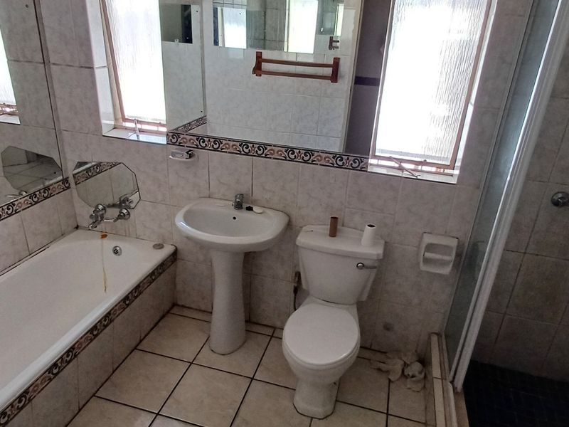 A dated bathroom featuring a pedestal basin, bathtub, toilet, and separate shower enclosure with tiled finishes throughout.