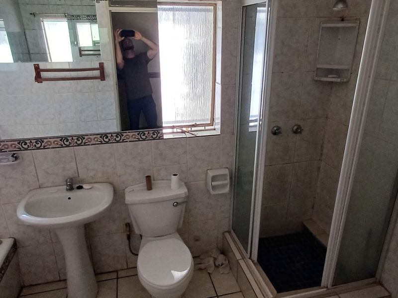 A dated bathroom featuring a pedestal basin, toilet, shower enclosure, and built-in bathtub with tiled finishes throughout.
