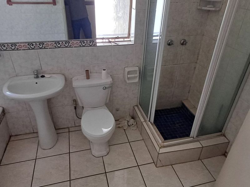 A functional bathroom featuring a pedestal basin, toilet, shower enclosure, and a built-in bathtub with tiled finishes throughout.