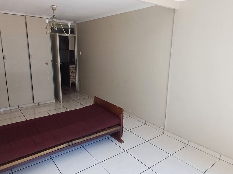 A bedroom featuring tiled flooring and built-in cupboards, offering a functional space ready for cosmetic updates and modern styling.