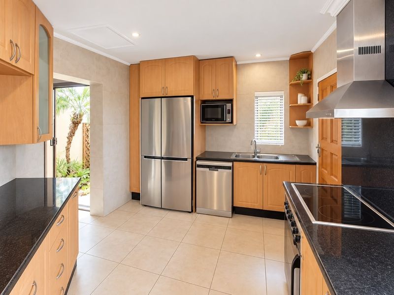 Well-appointed kitchen featuring light wood cabinetry, granite countertops, stainless steel appliances, and direct access to an outdoor area.