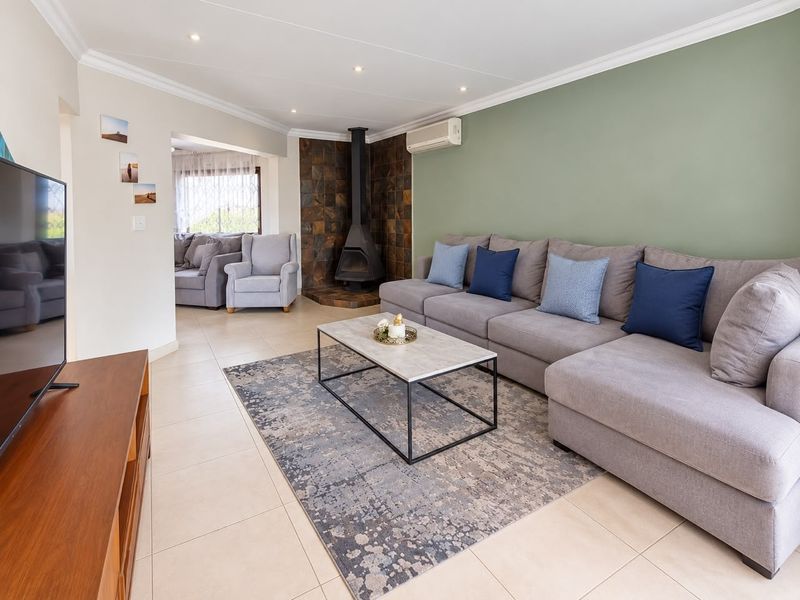Spacious living room featuring a tiled fireplace surround, split-system air conditioning, recessed lighting, and neutral tiled flooring throughout.