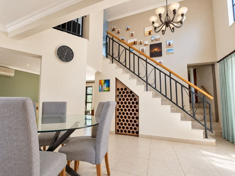 Open plan living area featuring a striking staircase with wrought iron railing, a custom built-in wine rack, and elegant tiled flooring.