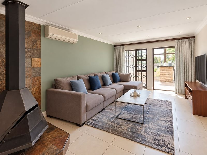 A well-maintained living room featuring a modern freestanding fireplace with stone cladding, tiled floors, and direct access to an outdoor patio area.