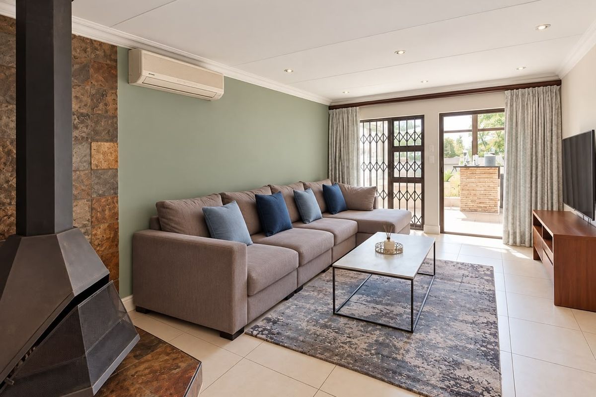 A well-maintained living room featuring a modern freestanding fireplace with stone cladding, tiled floors, and direct access to an outdoor patio area.