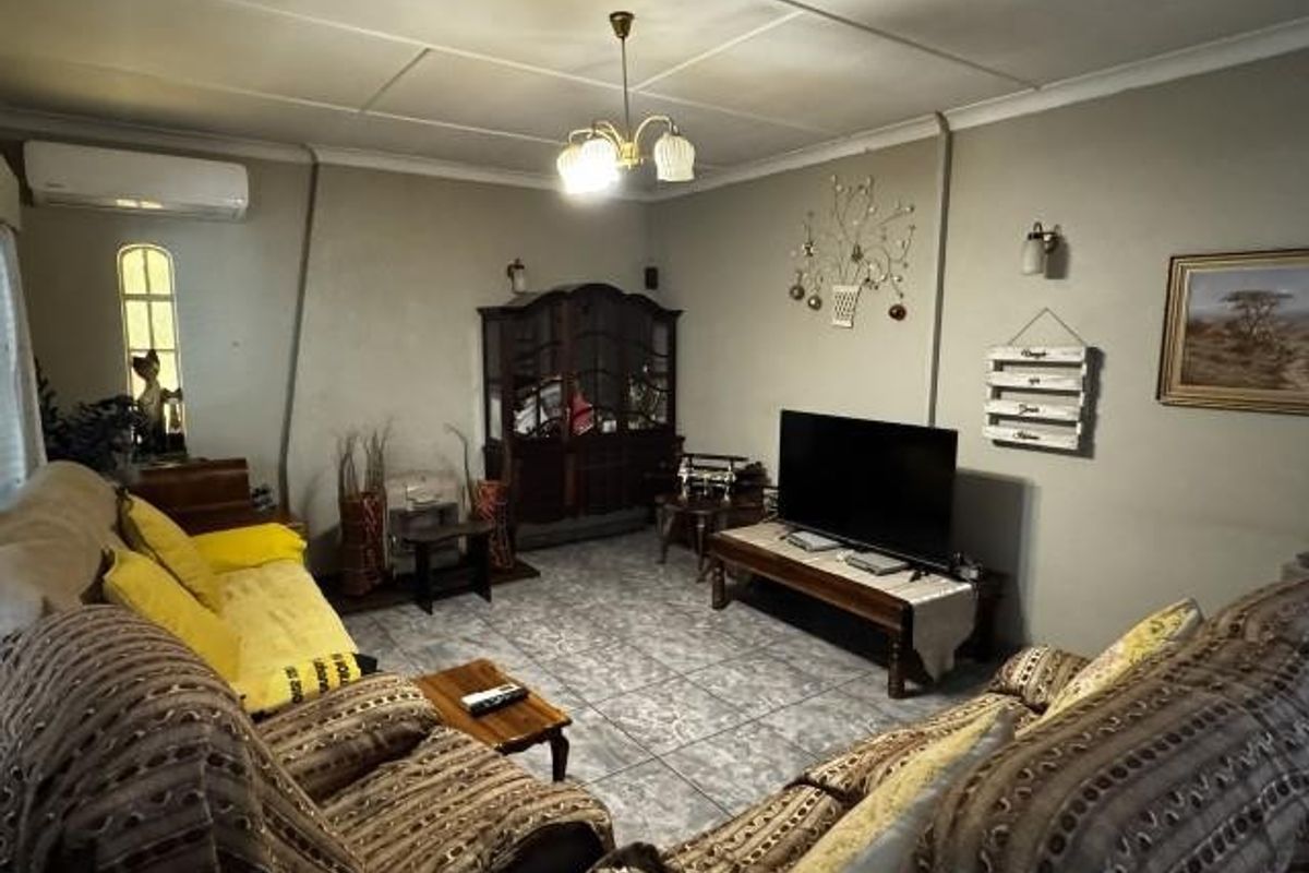 A living room featuring tiled flooring, a coved ceiling, and a wall-mounted split-system air conditioner.