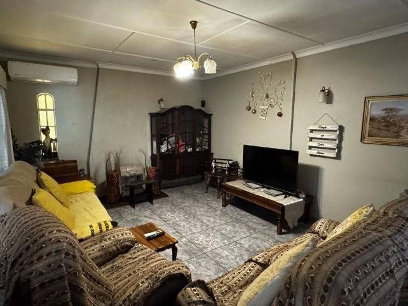A living room featuring tiled flooring, a coved ceiling, and a wall-mounted split-system air conditioner.