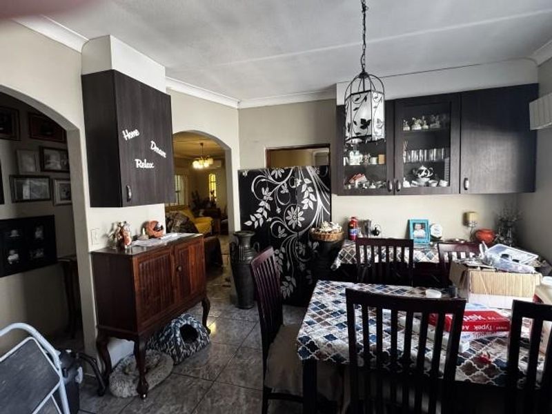 A dining area featuring dark wood built-in cabinetry with glass display sections, tiled flooring, and a decorative pendant light fixture.