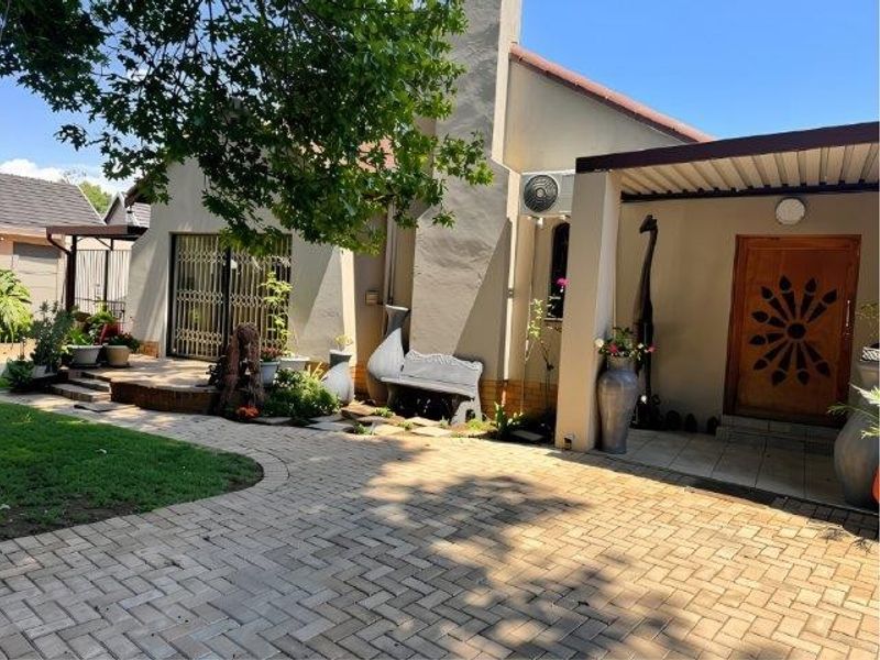 A well-maintained rear exterior view featuring a paved patio area, covered entrance, and a prominent chimney structure.