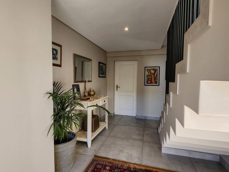 A bright and welcoming entrance hall featuring modern tiled flooring and a contemporary staircase with a sleek balustrade.