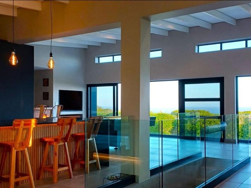 Modern open-plan living area featuring a sleek kitchen with built-in appliances, exposed beam ceilings, and expansive sliding doors opening to scenic views.