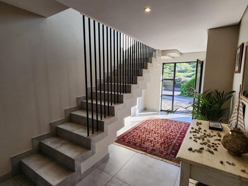 Bright and modern entrance hall featuring a tiled staircase with a sleek metal balustrade and direct access to the exterior.