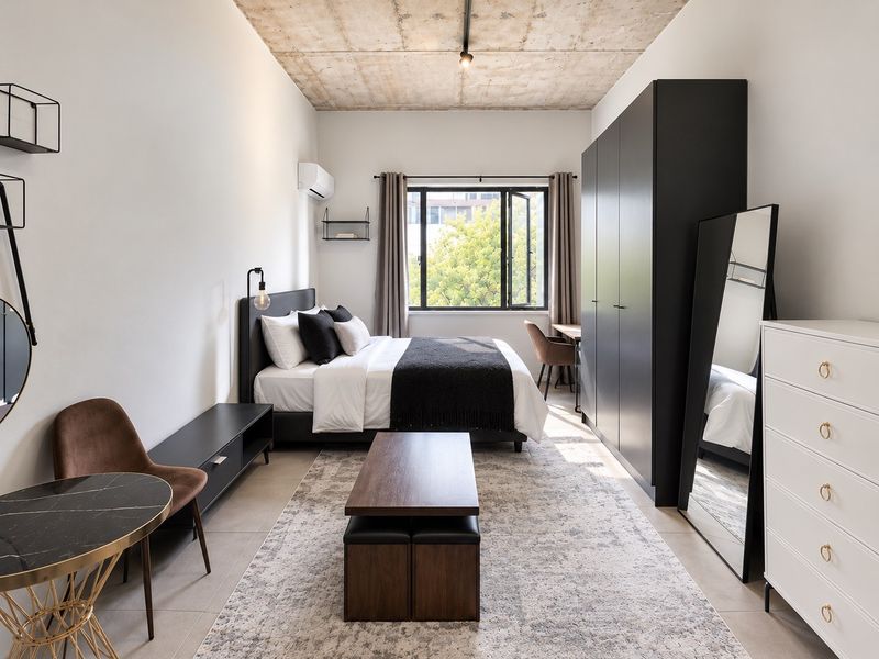 Modern bedroom featuring an exposed concrete ceiling, tiled flooring, built-in wardrobe, and a split-system air conditioner.
