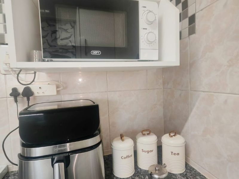 A close-up view of a kitchen counter area featuring a built-in microwave, granite worktop, and decorative tiled backsplash.