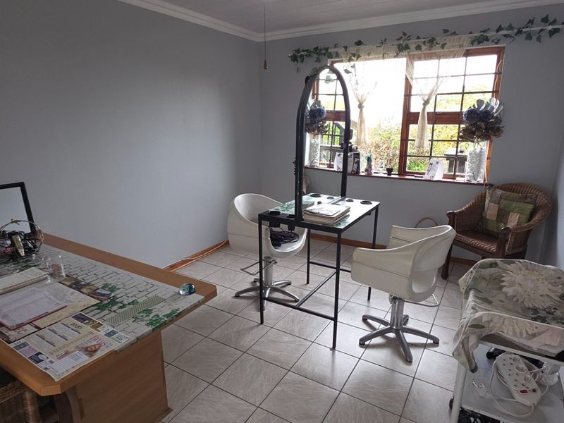 A functional office space featuring tiled flooring and a window with security bars, suitable for a home workspace or studio.