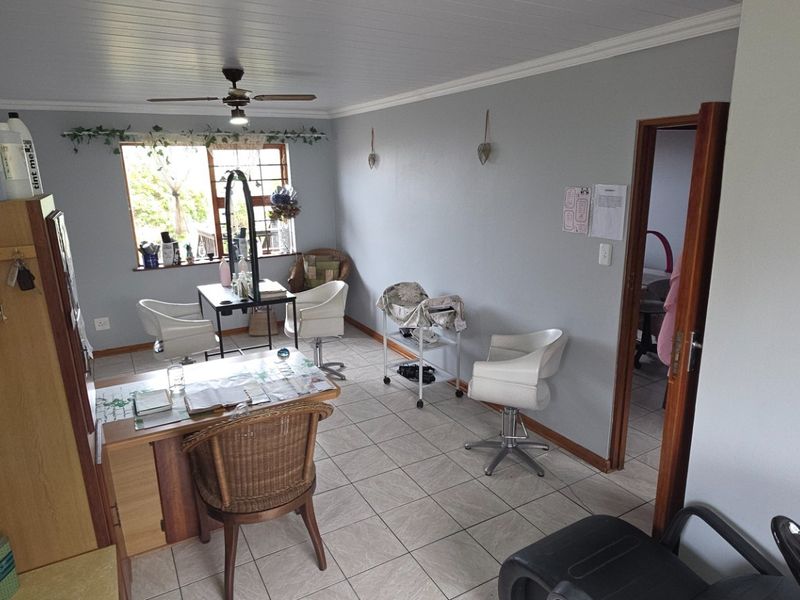 A functional room currently utilized as a salon space, featuring tiled flooring, a ceiling fan, and neutral wall finishes.