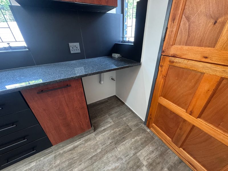 A functional laundry area featuring granite countertops, built-in cabinetry, and tiled flooring with dedicated plumbing connections for appliances.