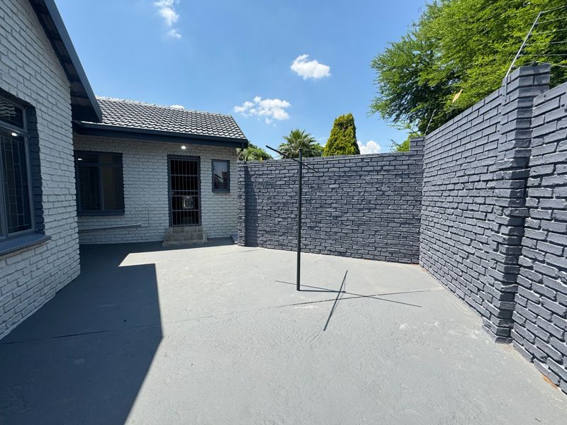 A private rear courtyard featuring painted brick walls, a concrete patio area, and secure perimeter fencing.