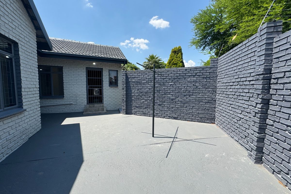 A private rear courtyard featuring painted brick walls, a concrete patio area, and secure perimeter fencing.