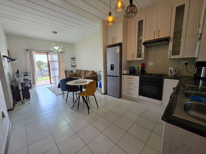 Open-plan living and kitchen area featuring tiled flooring, modern cabinetry, built-in appliances, and direct access to an outdoor patio through sliding glass doors.