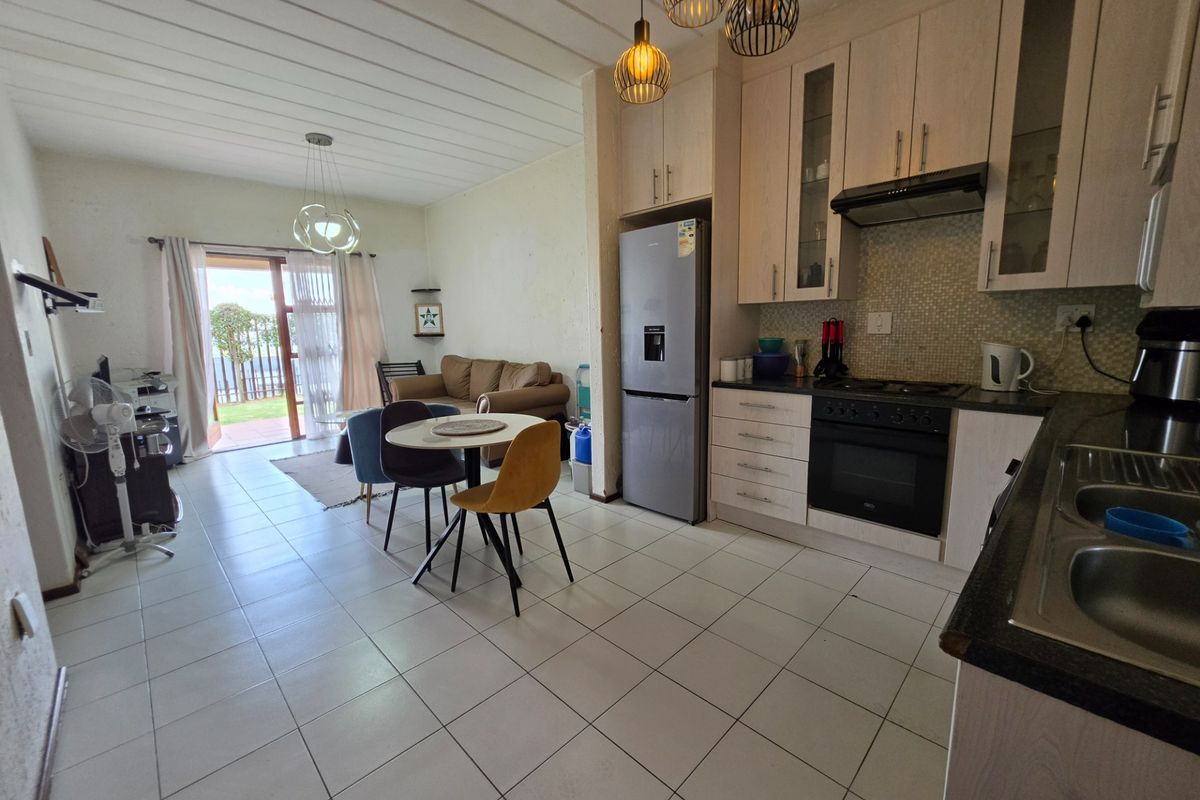 Open-plan living and kitchen area featuring tiled flooring, modern cabinetry, built-in appliances, and direct access to an outdoor patio through sliding glass doors.