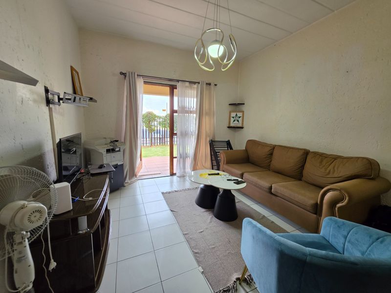 A living room featuring tiled flooring, textured walls, and a sliding glass door providing access to an outdoor patio area.