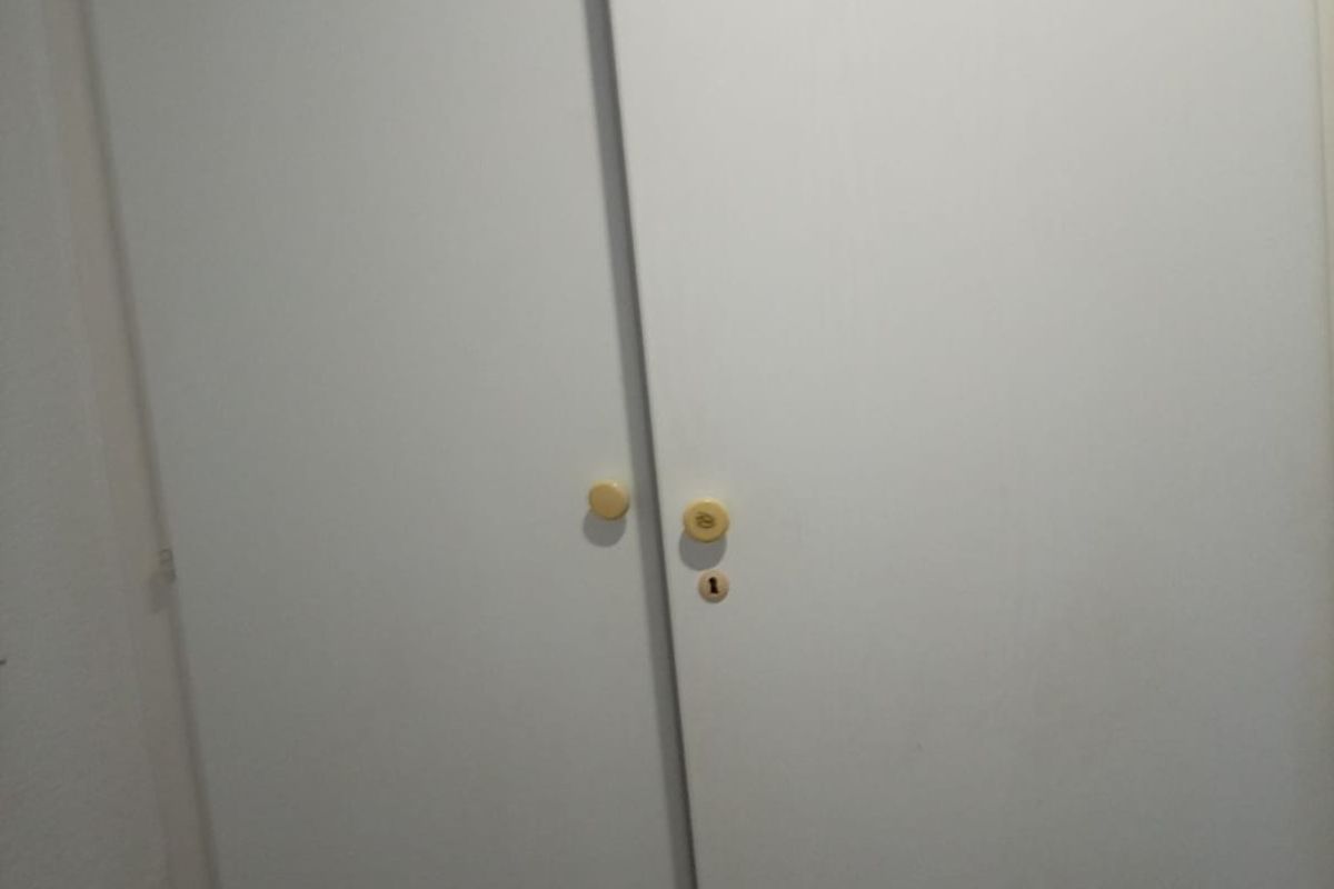 A close-up view of a standard white built-in wardrobe with simple round knobs.