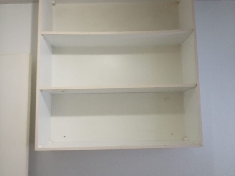 A simple wall-mounted white shelving unit fixed to the wall.