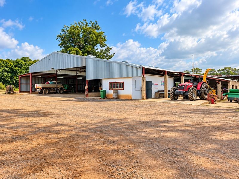 A large multi-bay agricultural shed with a corrugated metal roof and concrete apron, suitable for farm equipment storage and operational use.