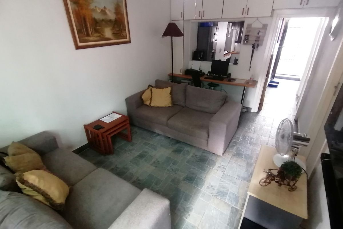 A living room featuring tiled flooring, built-in overhead storage cabinets, and a pass-through window connecting to the adjacent kitchen area.